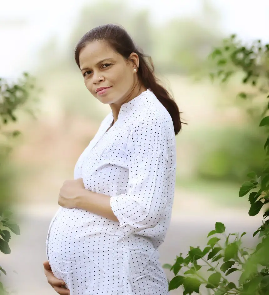 A pregnant woman standing in the middle of a tree.