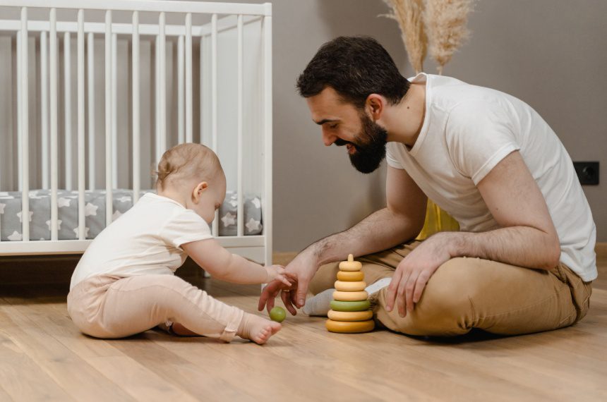 A man and baby playing with toys on the floor.