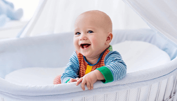A baby is smiling in his crib.